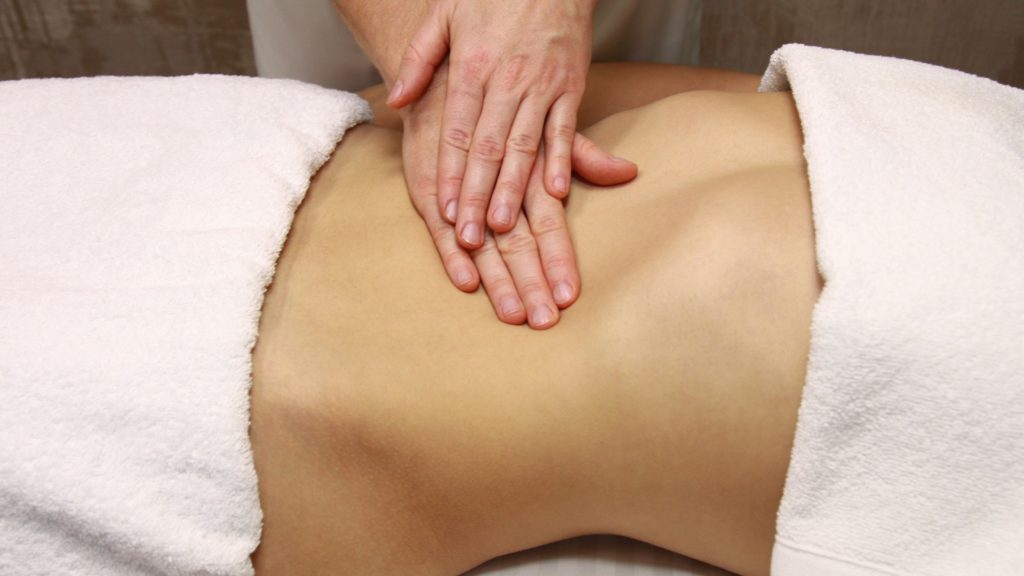 Women's abdomen being massaged by two hands