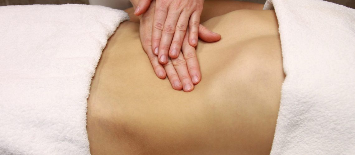 Women's abdomen being massaged by two hands
